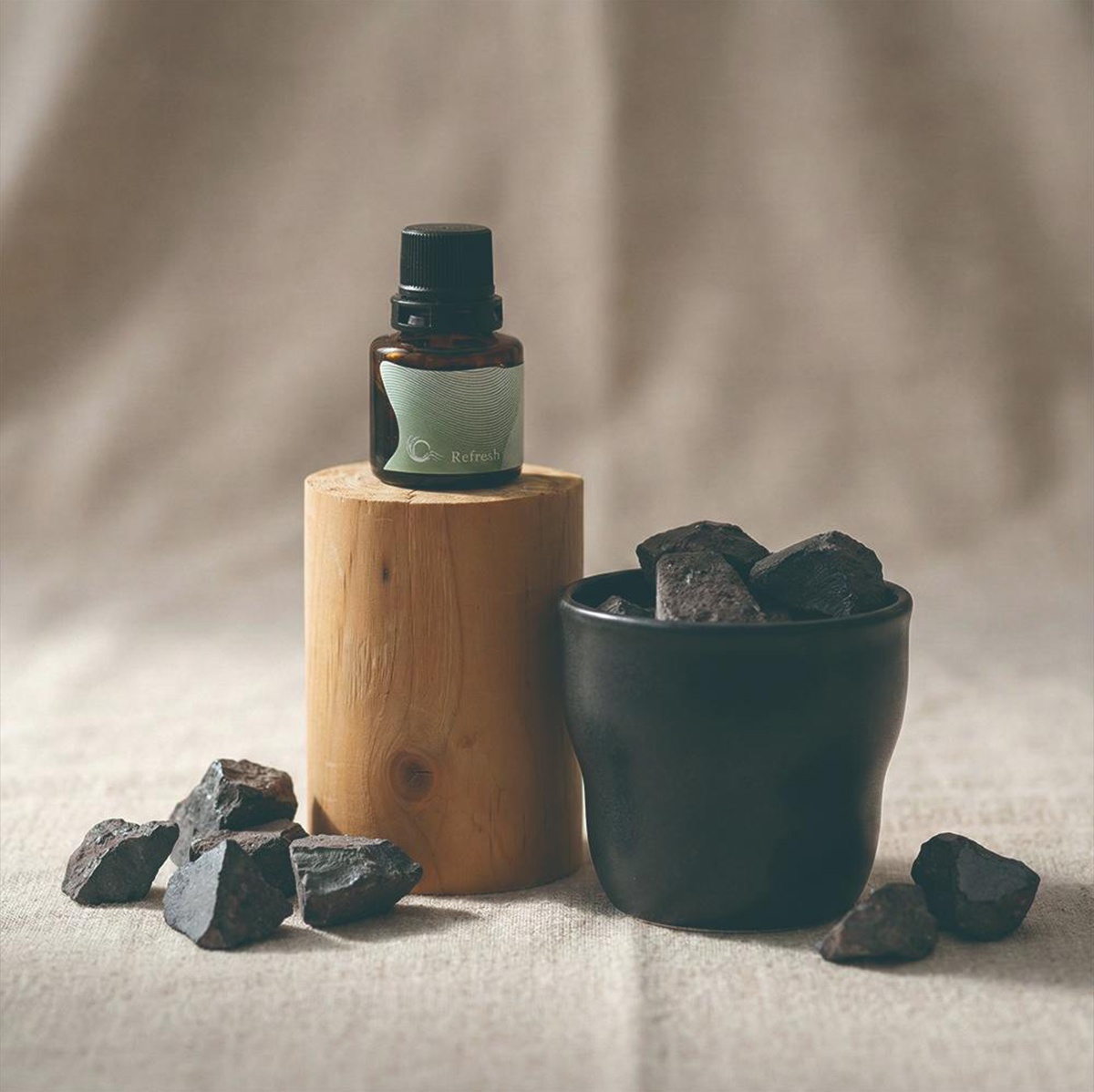 KYARA aroma recolte 擴香組，展示一瓶標有 Refresh 字樣的精油，放置在木頭底座上，旁邊有一個裝有擴香石的黑色陶杯。