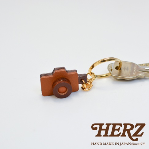 職人手作皮革相機造型鑰匙圈，咖啡色皮革製作，搭配金色鑰匙圈，風格簡約。