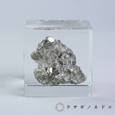 透明立方體中封存著一塊黃鐵礦，礦石呈現金屬光澤的銀灰色，具有多個立體晶面。