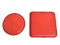 兩個紅色的皮革坐墊，一個為圓形，一個為方形，皆採用手工縫線裝飾。