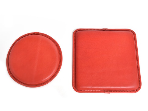 兩個紅色的皮革坐墊，一個為圓形，一個為方形，皆採用手工縫線裝飾。