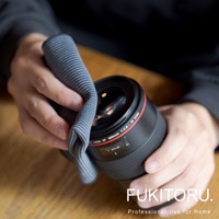 一雙手正用灰色超細纖維清潔布擦拭黑色相機鏡頭。