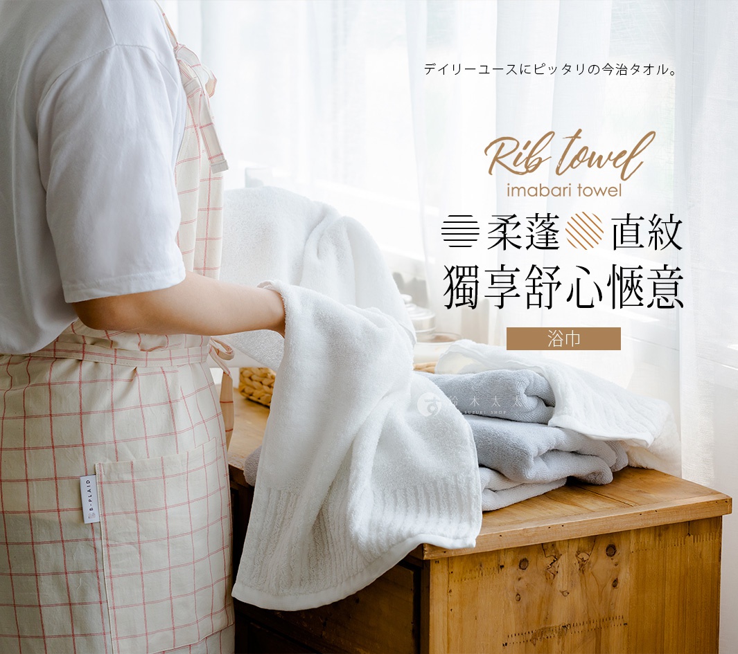 一雙手拿著一條白色長毛柔暖速乾直紋浴巾，背景是木製櫃子和窗簾，櫃子上疊放著其他毛巾。