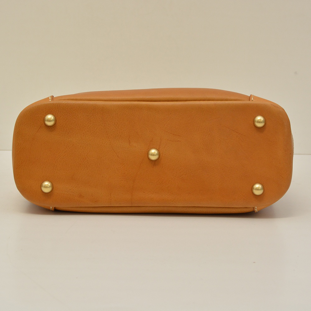 駝色皮革波士頓包底部，設有五個金色金屬腳釘，用於保護包包底部，展現職人手作質感。