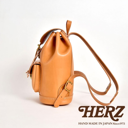 職人手作經典後背包 R-4，以自然色皮革製成，設計簡約，附有側邊小口袋、束繩開口及可調節式肩帶，搭配金屬扣環，呈現經典復古風格。