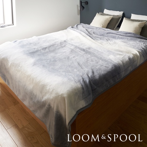 抗菌短絨舒柔雙人毯，採用淺灰與白色漸層潑墨印花，觸感柔軟，鋪陳在雙人床上。