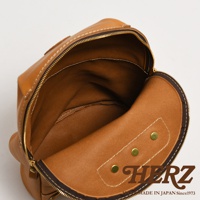 職人手作皮革大開口圓角後背包，展示棕褐色皮革材質，內部空間寬敞，附有拉鍊開合及金屬卯釘裝飾。