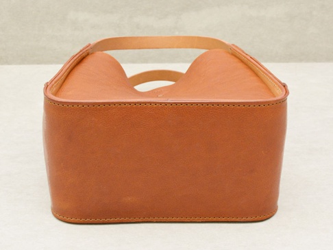 棕褐色皮革製成的方形托特包，雙提把設計，包身有縫線細節。