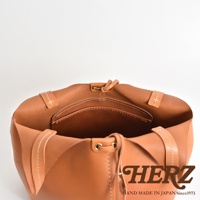 棕色皮革球形肩掛托特包，展示包內結構，帶有內袋及抽繩設計，整體手工縫線精緻，皮革質感自然。