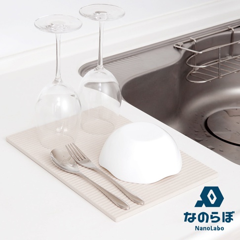 廚房水槽旁，兩只倒置的酒杯放在吸水墊上，旁邊還有一個白碗、一把湯匙和一把叉子，標有NANOLABO的Logo。