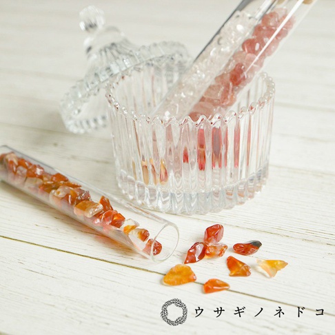 透明玻璃試管中裝有橙色和紅色的礦石碎塊，另有兩支試管和一個帶蓋的壓花透明玻璃罐。