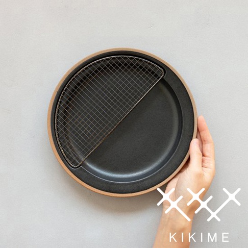 美濃燒瀝油餐盤，黑色陶瓷盤面，附帶半月形金屬瀝油網，盤緣為原色陶土。