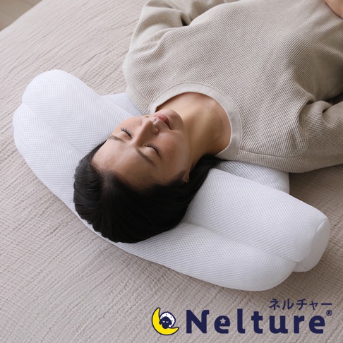 一名女子平躺在床墊上，頭部枕在一個白色、網狀材質的瑜珈感安睡枕上。枕頭設計有凹槽，能支撐頭部與頸部。