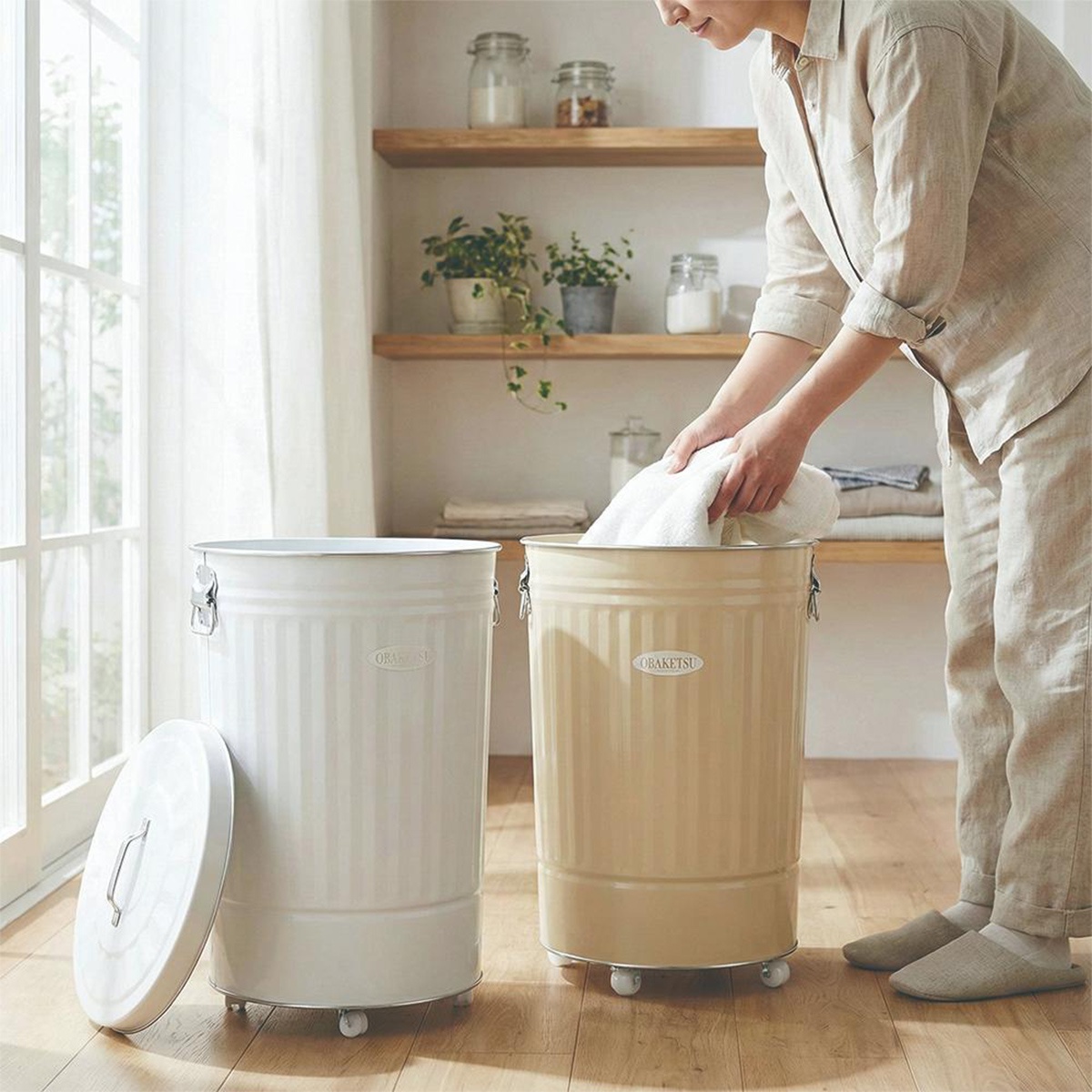 OBAKETSU 附輪垃圾桶，米白色與黃褐色桶身，附有蓋子，一人正將毛巾放入黃褐色垃圾桶中