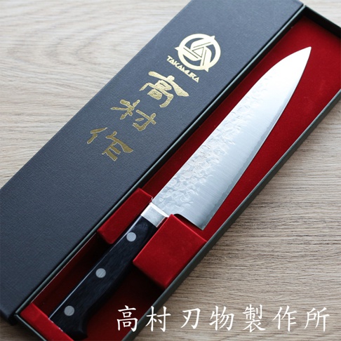 VG10不鏽鋼鎚目牛刀，18公分，刀刃為銀色，帶有鎚紋和 Damascus 紋路，黑色握柄，置於黑色包裝盒內的紅色絨布內襯中。