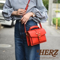 紅色皮革迷你單肩包，帶有頂部提把、可調式斜背帶、金色金屬扣環和搭扣。