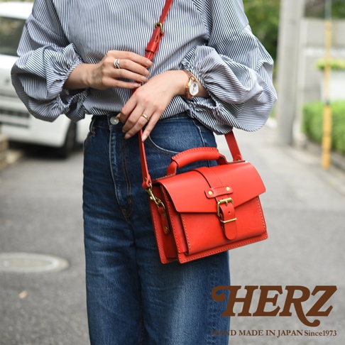 紅色皮革迷你單肩包，帶有頂部提把、可調式斜背帶、金色金屬扣環和搭扣。