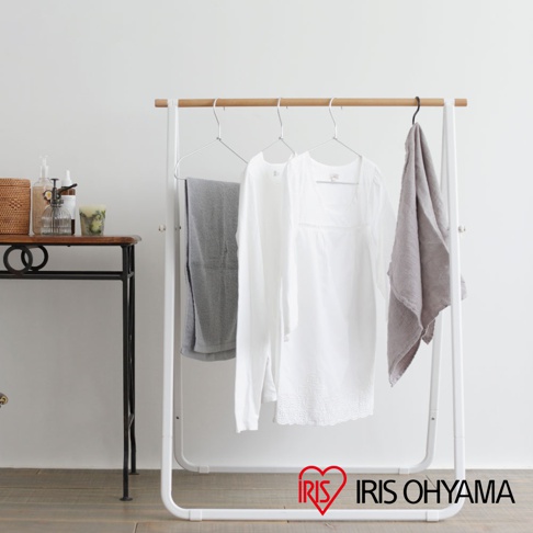 白色金屬曬衣架，頂部為原木橫桿，掛有灰色毛巾、白色長袖上衣和灰色方巾。