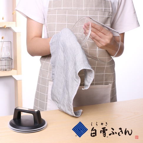 一名穿著格紋圍裙的人正用一塊淺灰色、網狀紋理的拭巾擦拭玻璃杯。