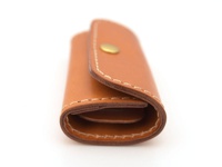 一件棕色皮革製的四鉤鑰匙包，附有金色按扣和米色縫線，展示了簡潔的設計。