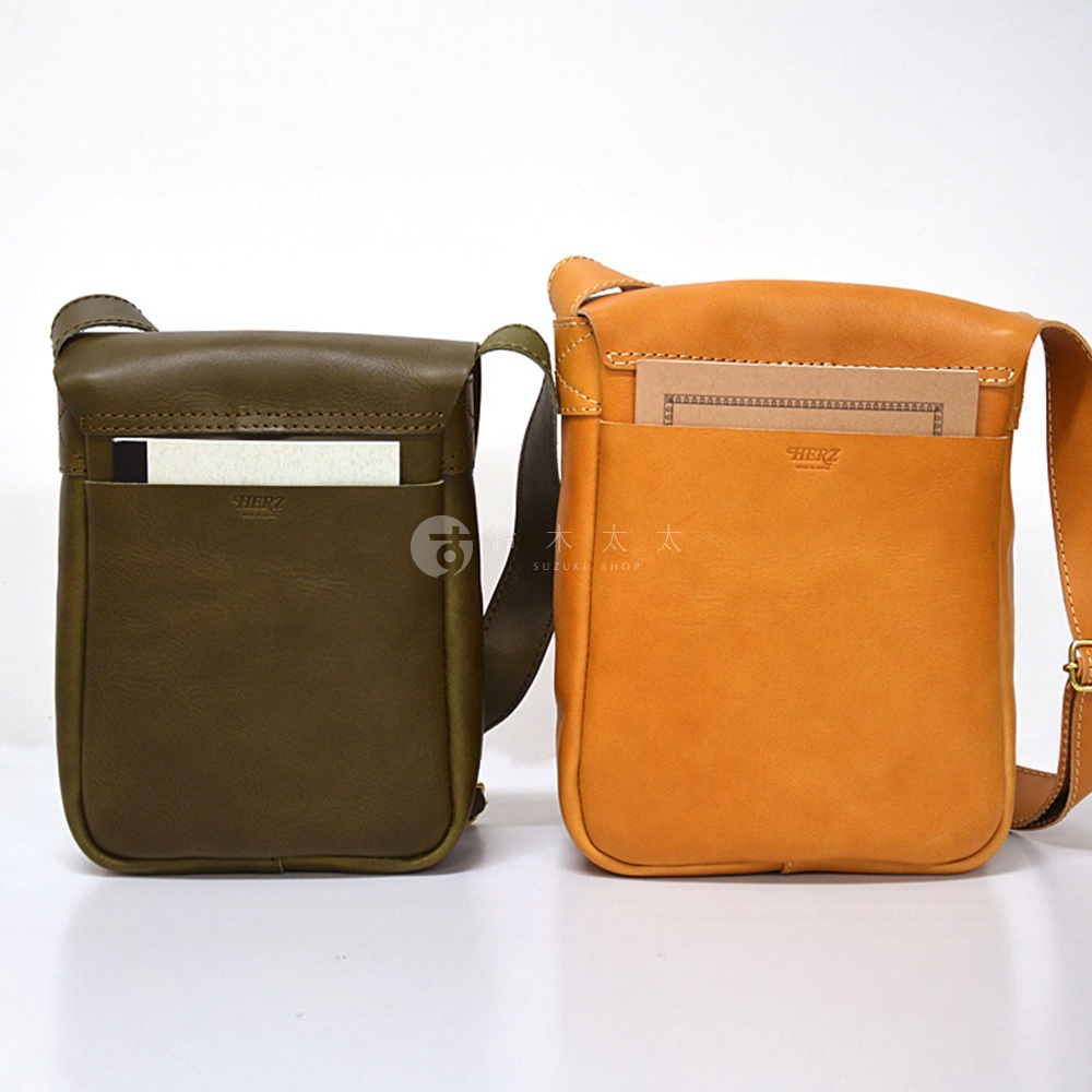 兩款日本HERZ職人手作皮革軟皮直式斜背包，一款為墨綠色，另一款為橘黃色，皆帶有品牌標誌。