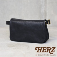 黑色皮革斜背包，款式簡約，配有可調節的金色搭扣。