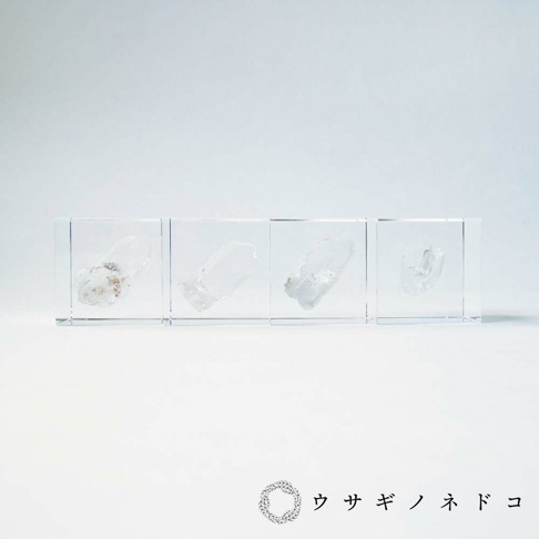 四個透明立方體展示盒，內含不同形狀的天然水晶礦石，色澤以透明、半透明為主，部分礦石帶有淺黃色或灰白色雜質。