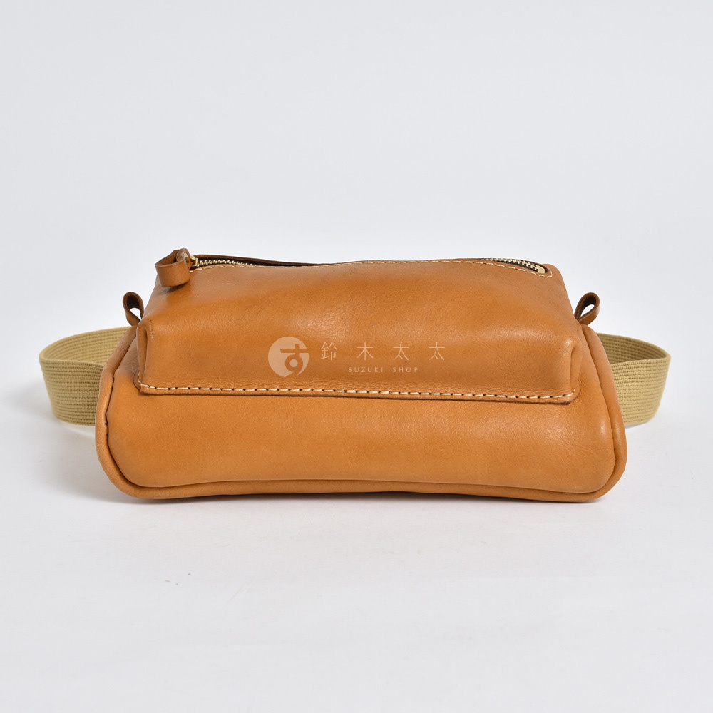 棕色皮革製成的手工兩用腰掛斜背包，配有米色織帶，頂部有拉鍊開合。