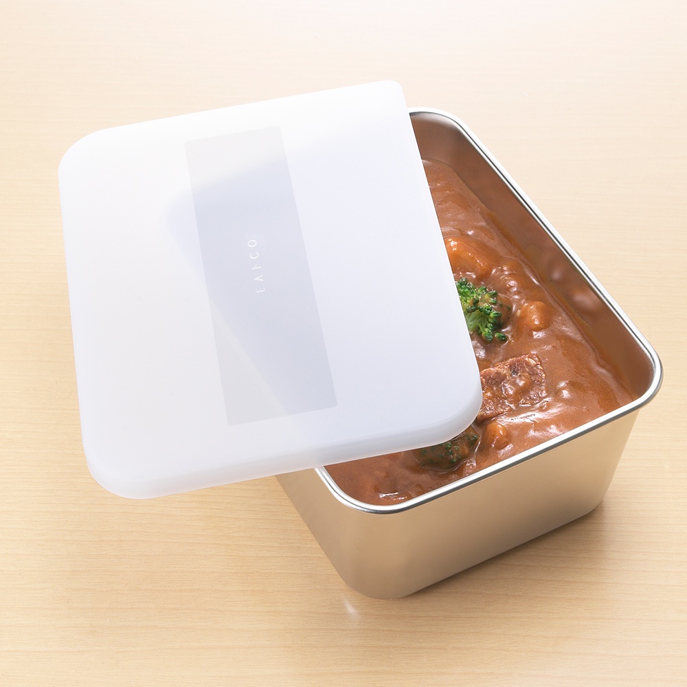日本製不鏽鋼食物儲存盒，附有白色塑膠蓋。盒內裝有燉牛肉咖哩，上面點綴著少許綠色蔬菜。