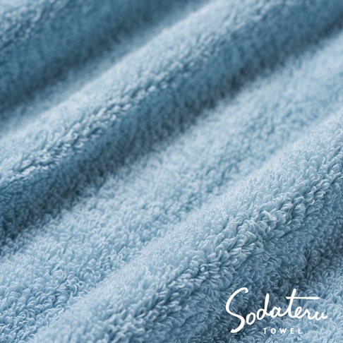 淺藍色柔軟蓬鬆的浴巾特寫，展示其細膩的絨毛紋理。