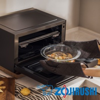 STAN美型烘烤微波爐 ES-SAF26，黑色機身，內部有烤架。一雙深棕色隔熱手套正取出一個裝有燉煮食物的透明玻璃碗，碗內有肉塊、馬鈴薯、紅蘿蔔和蔥段，冒著熱氣。