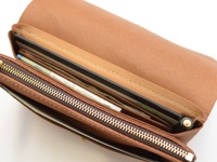 職人手作皮革旅行長夾，淺棕色牛皮材質，內有護照、機票、紙鈔和一支筆，拉鍊為金色。