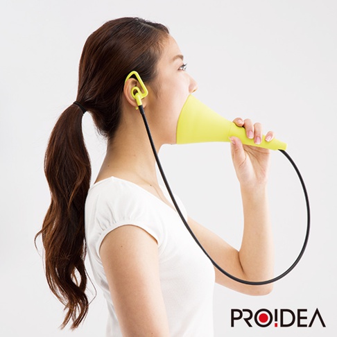 一名女性使用亮黃色、喇叭狀的消音高歌器，其一端插入耳內，另一端置於嘴邊。產品由塑膠製成，並附有黑色連接線。