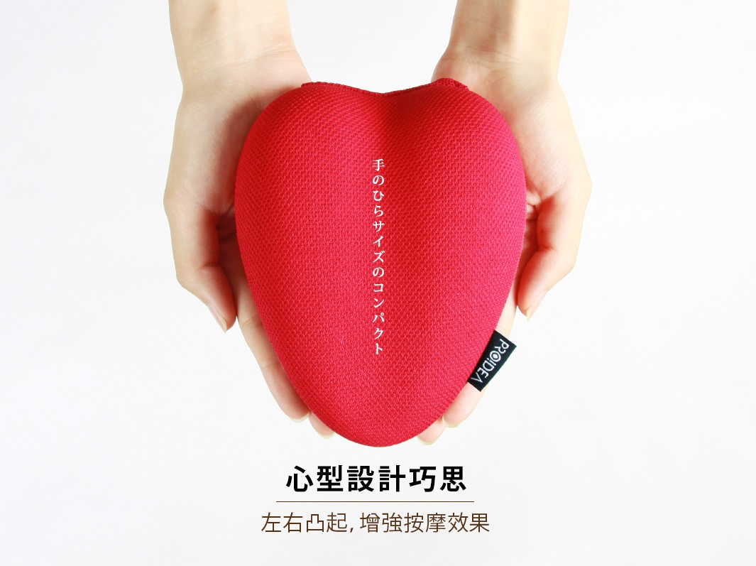 雙手捧著一個紅色愛心形狀的指壓枕，枕面為網狀織物材質，左側有日文說明文字，右側有黑色品牌標籤。