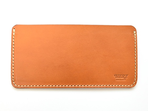 職人手作皮革紙鈔專用收納夾 (WL-91)，以溫暖的棕色皮革製成，邊緣以米白色縫線細緻縫合。右下角壓印有「HERZ」及「MADE IN JAPAN」字樣。