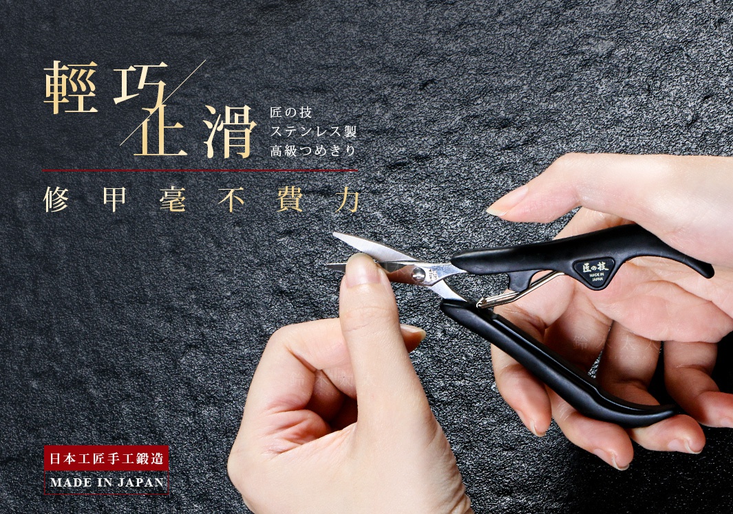一雙手持著黑色防滑握柄的不鏽鋼指甲剪，剪刀的刀刃部分為銀色金屬材質，握柄上有日文標誌。