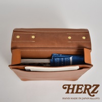 職人手作皮革三口袋三用後背包A-19-R，展現棕色皮革紋理，內部收納雜誌與藍色印花頭巾，並有金色金屬釦飾。