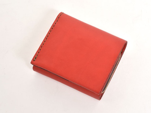 鮮紅色皮革製成的職人手作直式卡片收納雙折短夾，側面有拉鍊，邊緣以縫線裝飾。