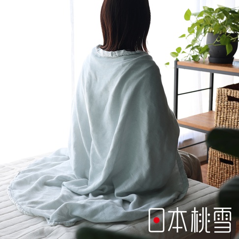 淺藍色二層紗半毯，質地輕柔，搭在一位女士肩上，毯子垂落在身旁，營造舒適氛圍。