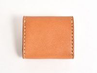 一個簡約的棕褐色皮革雙折收納零錢包，採用手工縫線裝飾，整體呈現質樸的設計風格。