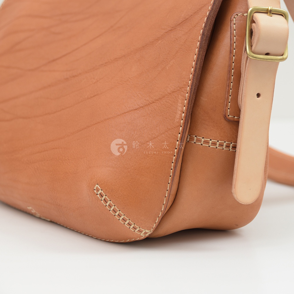 職人手作皮革郵差包，淺棕色，皮革材質，帶有金屬扣環及縫線細節。
