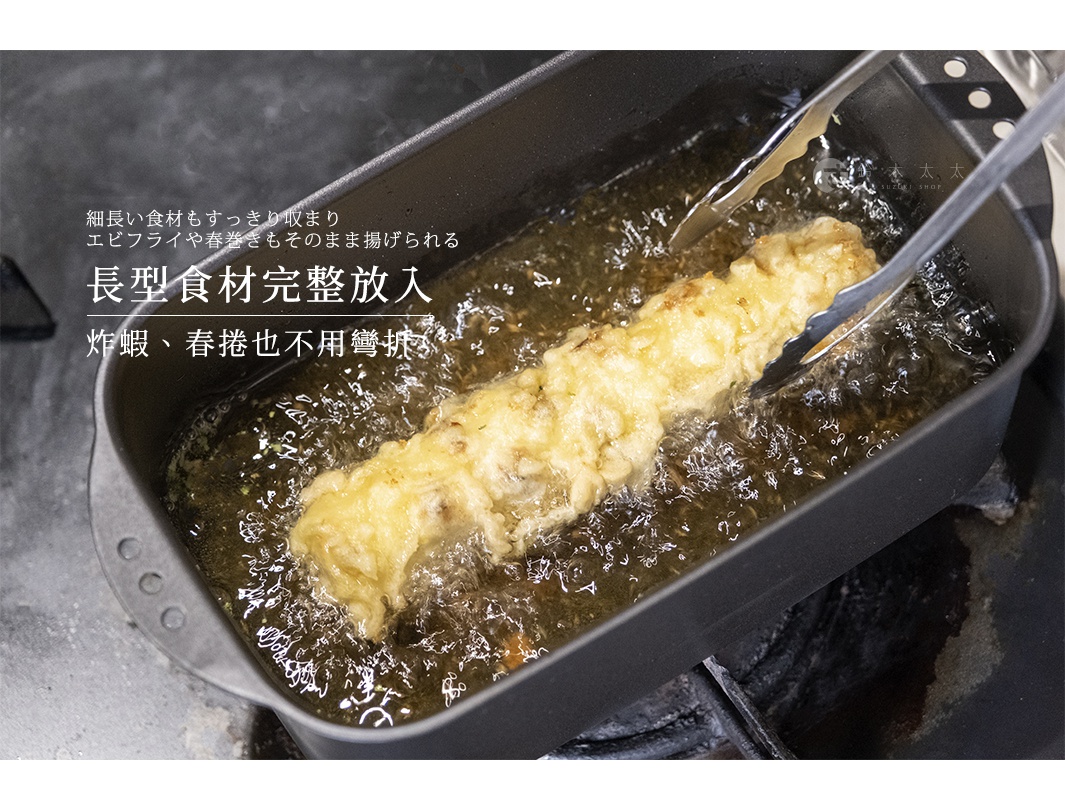 細長造型的黑色長方形炸鍋正放在瓦斯爐上，熱油中炸著一條外皮金黃酥脆的長形天婦羅，一雙金屬料理夾正夾住炸物進行烹調，呈現出方便油炸長型食材的使用情境。