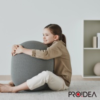 一名小女孩擁抱著一個灰色的針織平衡球，球體呈橢圓形，表面有細密的紋理。