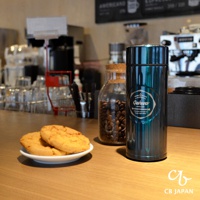 金屬材質的城市咖啡保溫杯，瓶身呈現深邃的綠松石色，印有白色圓形標誌，內容包含「THIRD WAVE COFFEE Qahwa PORTLAND」等字樣，質感光滑。杯旁擺放著兩個餅乾。