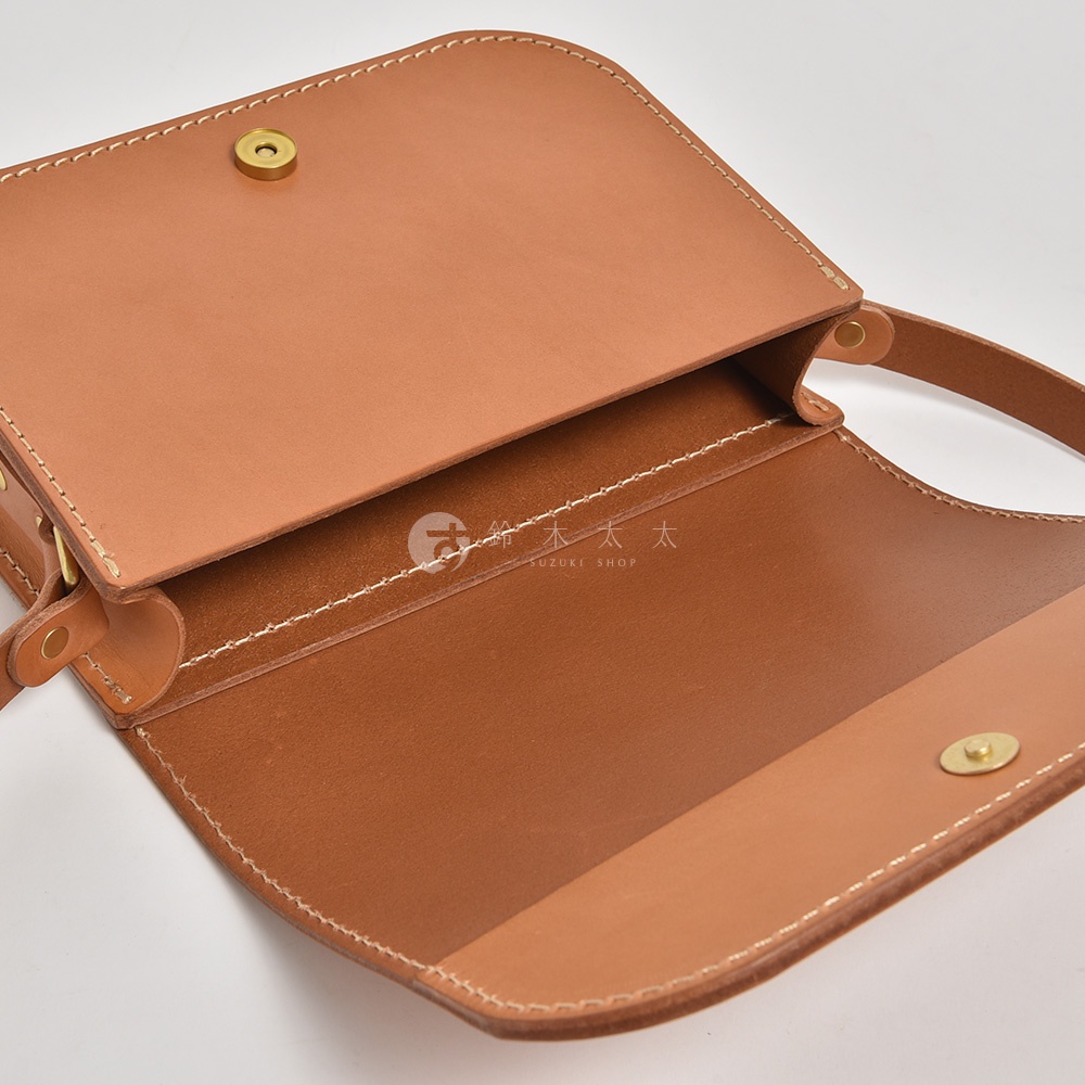 職人手作皮革翻蓋橫式單肩包，採用棕褐色皮革材質，搭配白色車縫線，設有翻蓋式開口與金屬釦。