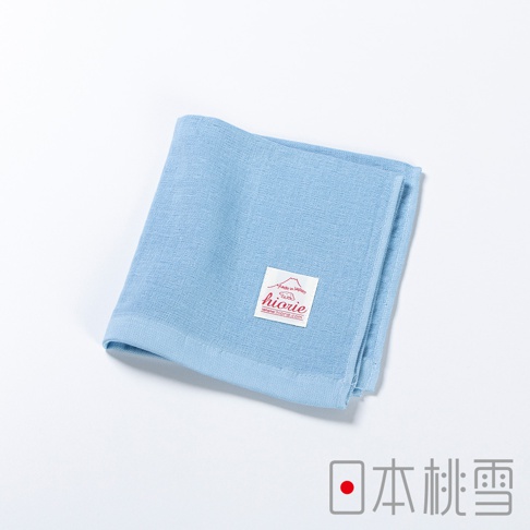 淡藍色大人風紗布方巾，材質為紗布，質地柔軟，帶有品牌標籤，標籤上有「Made in Japan」字樣及山形圖案，整體呈現簡約的日系風格。