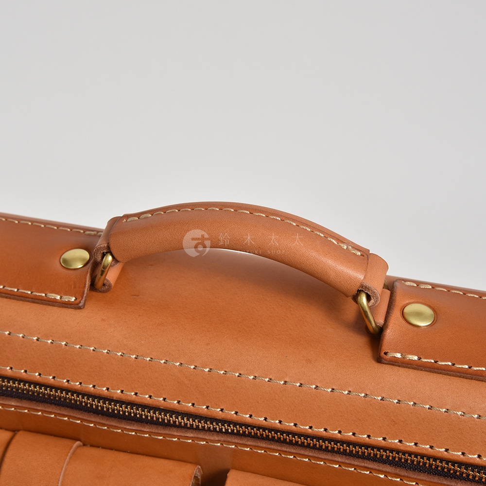職人手作皮革三用後背包 A-19-R，焦糖棕色，展示皮革提把、金屬卯釘及拉鍊細節，縫線清晰，材質為天然皮革。