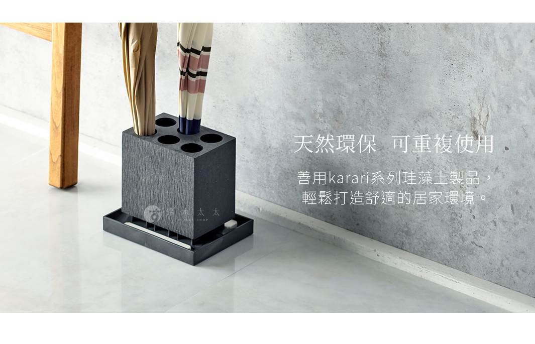 深灰色珪藻土製成的六孔傘架，帶有可拆卸的集水盤，置於淺色地板上，旁邊有木製家具的腿部，傘架中插入了幾把深色和彩色條紋的傘。
