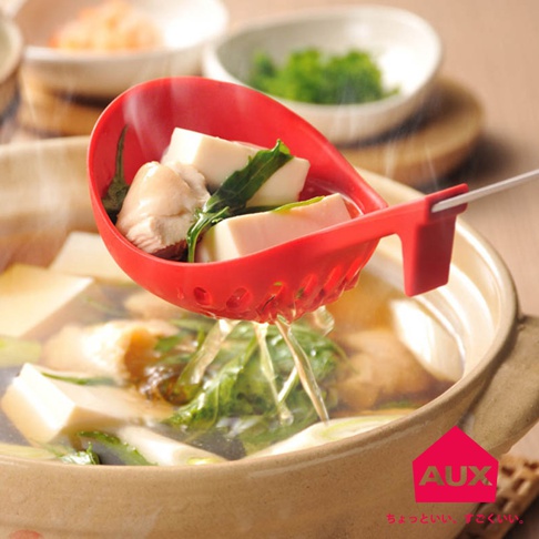 紅色的 UCHICOOK 不沾桌多用濾水湯匙，湯匙內盛有豆腐、雞肉和青菜，湯匙帶有濾水孔，正從火鍋中撈起食材，湯汁從濾孔滴落。
