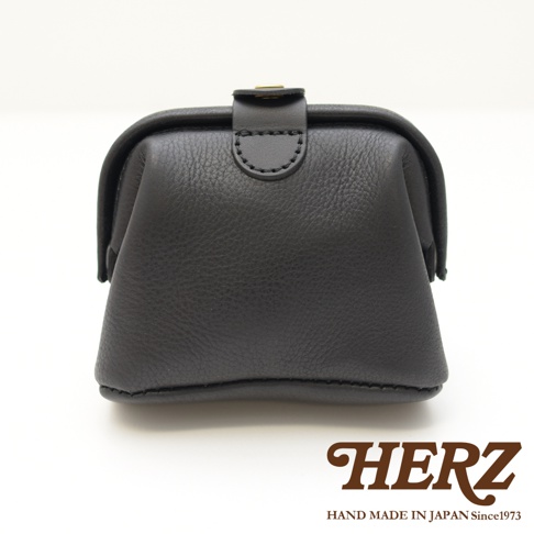 黑色皮革製成的手作口金化妝包，帶有金屬扣環，包身呈現醫藥包造型，底部和邊緣有明顯縫線。